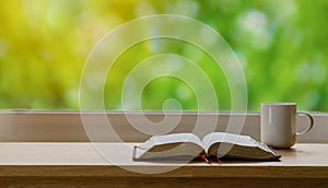 Open Bible and coffee in the morning on a wood table with green nature backgound photo