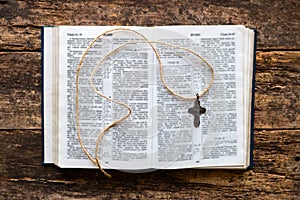 Open bible and cross on a wooden background