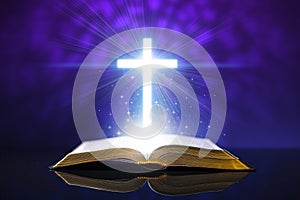 Open bible on a glass desk with a glowing cross