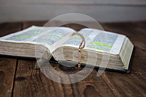 A open bible and golden cross on wooden background