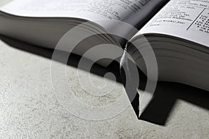 Open Bible on light gray table, closeup with space for text. Christian religious book