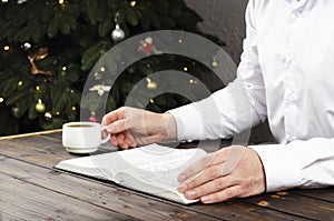 Open Bible. The man in the shirt. A cup of coffee. Office businessman. Christmas. Christmas tree.