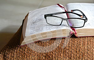 Open bible on a pilllow, with reading glasses on top of it