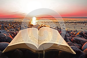 Open bible spiritual light on seashore