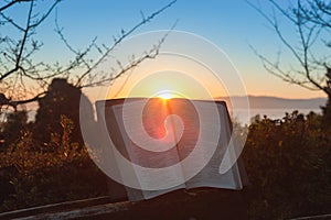 Open bible at sunrise with flare in Fuji city, Japan. Background with sea, mountain and blue sky