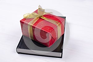 An open Bible on the table. A gift on a book. A red gift-wrapped box with a gold bow. A gift from God