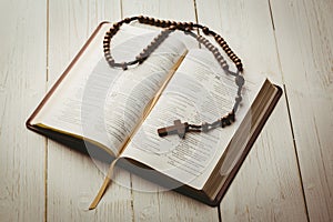 Open bible and wooden rosary beads