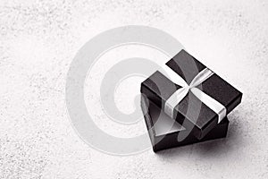 Open black box with white ribbon on a light background. Gift wrapping with empty place for text