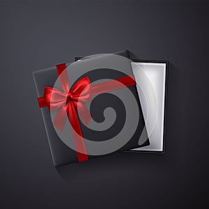 Open black empty gift box with red bow and ribbon on dark background. Top view. Template for your presentation, banner or poster.