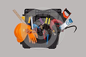 An open black plastic tool kit box with an construction orange protective helmet and various hand tools isolated on a grey backgro