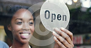 Open, black woman and business owner with a door sign to welcome customers or clients in retail store. Employees