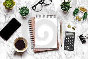 Open blank note book, glasses, cup of coffee, pen, smartphone, succulents on marble table