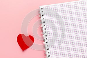 Open blank notebook and red paper heart on pink background. Valentine`s Day and romantic holiday concept. Love message.