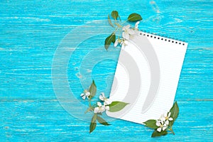 open blank notepad with blooming on turquoise wooden background