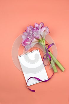 Open blank notepad and bouquet of pink flowers on table top view in flat lay style