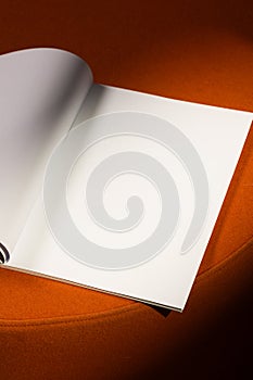 open blank page of a notebook or magazine rests on a soft orange surface