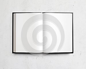 Open blank textbook on white stucco wall