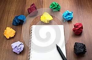 Open blank white book and pencil with group of colorful crumpled