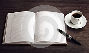 Open a blank white notebook, pen and coffee on the desk