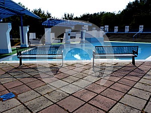 Open blue kids` swimming pool with benches and awnings