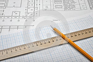 Open blueprints on wooden table background with a pencil and a ruler lying beside.