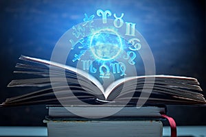 Open book on astrology on a dark background. The glowing magical globe with signs of the zodiac in the blue light