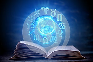 Open book on astrology on a dark background. Glowing magical globe with signs of the zodiac in the blue light