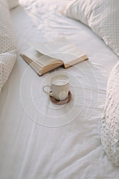 Open book on bedsheets and a cup of coffee. Good morning. Breakfast in bed. flat lay