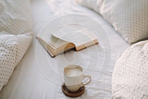 Open book on bedsheets and a cup of coffee. Good morning. Breakfast in bed. flat lay