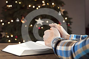 Open book Bible. Hands in prayer. Praying for Christmas.