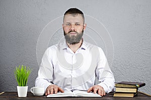 Open book Bible. The man is sitting at the table. Book reading. Desktop.