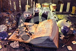 Open book with black magic spells, pentagram, ritual objects and candles on witch table