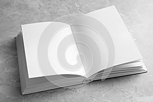 Open book with blank pages on grey marble background. Mock up for design