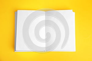 Open book with blank pages on yellow background