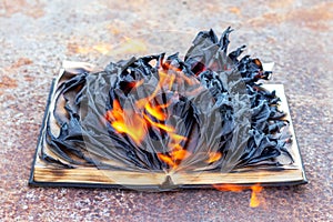 An open book with charred pages is burning photo