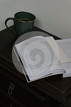 Open book and coffee cup on bedside table
