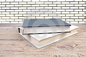open book. Composition with hardback books, fanned pages on wooden deck table and Brick wall background. Books stacking. Back to