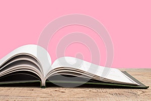 open book. Composition with hardback books, fanned pages on wooden deck table and pink background. Books stacking. Back to school