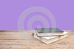 open book. Composition with hardback books, fanned pages on wooden deck table and purple background. Books stacking. Back to