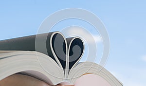 Open book with curled leaves in the shape of a heart