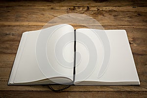 Open book on dark wooden desk, blank, with copy-space.