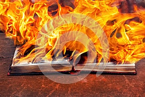The open book is engulfed in fire. Burning of books, banned literature photo