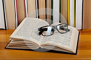 Open book, glasses hardback colorful books on wooden table. Back to school. Copy space for text. Education business