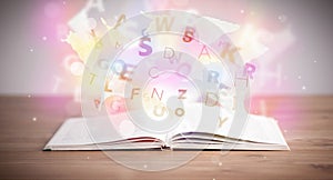 Open book with glowing letters on concrete background