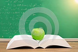 Open book with green apple in concept education.