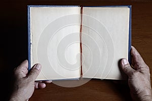 Open book with hand on wooden background. Conceptual composition about reading a book
