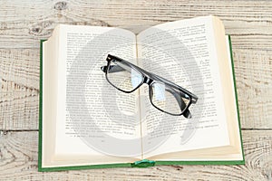 Open book, hardback books, glasses on wooden table. Back to school. Education. Copy space for text