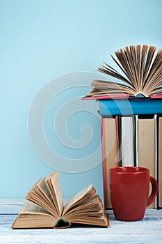 Open book, hardback books on wooden table and blue background. Back to school. Copy space for text