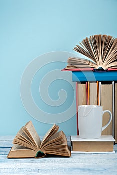 Open book, hardback books on wooden table and blue background. Back to school. Copy space for text.