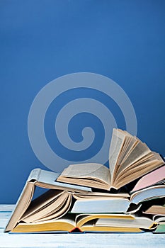 Open book, hardback colorful books on wooden table, blue background. Back to school. Copy space for text. Education